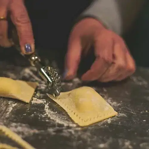 Person cutting ravioli with pasta cutter (Maria)